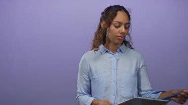 Mor stüdyoya bakarken elinde pano tutan ve notlar okuyan kadın; konsantrasyon odaklı organizasyon.