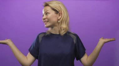 Genç sarışın kadın gülümser ve mor stüdyoda yana bakarken ellerini uzatır; merak ve seçim.