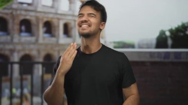 Roma 'nın tarihi kolezyumunun önünde gülümseyen genç bir adam canlı bir şehir caddesinde Roma' nın canlı açık hava atmosferini yakalıyor..