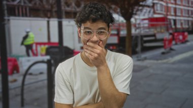 Şehrin işlek caddesinde inşaat bariyerlerinin önünde ağzı kapalı genç bir İspanyol adam, yorgunluk....