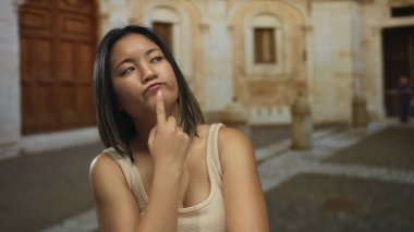 Bir yaz günü arka planda tarihi mimari olan günlük giysiler içinde şehir sokaklarında düşünceli bir ifadeyle dışarıda düşünen bir kadın..