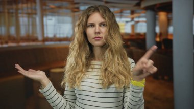 Bir kadın ofis ortamında, çizgili uzun saçlı, gösterişli, genç bir sarışın profili sergilerken elini reddediyor..