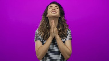 Stüdyo ortamında el ele dua eden kadın, yansıtıcı duruşunda gözler yükseldi; umut.