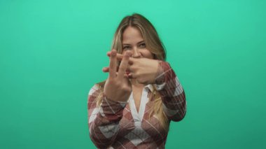 Profesyonel stüdyo ortamında parmaklarıyla hashtag işareti oluşturan gülümseyen sarışın kadın; sosyal medya eğilimi.