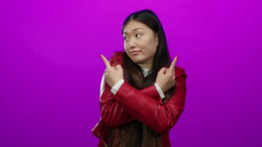 Kırmızı ceketli, uzun saçlı, parlak pembe arka planda jestleri olan bir kadın oyuncu karışıklığı ve yönü gösteriyor..