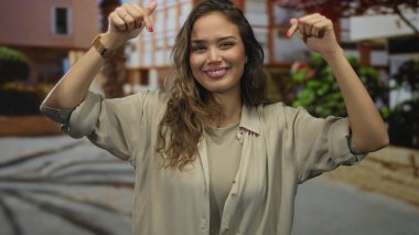 Kadın şehir dışındaki bir sokak sahnesini işaret ediyor, bina ve yapraklar yumuşak odak noktasında; vurgu.