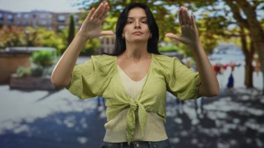 Sabahın erken saatlerinde kalabalık bir yaya caddesinde sakin bir jest yapmak için iki elini de havaya kaldıran kadın..