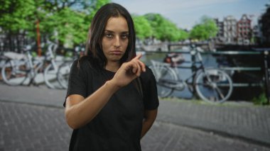 Amsterdam 'da park halindeki bir bisikletin yanında duran kadın başını yana eğiyor ve yana bakıyor; sessiz tefekkür.