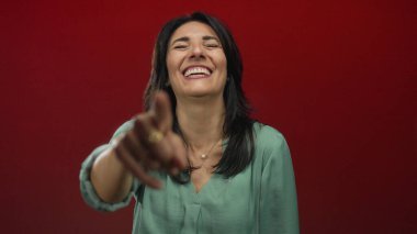 Stüdyoda gülümseyen ve kamerayı işaret eden orta yaşlı İspanyol kadın, neşe ve kahkaha.