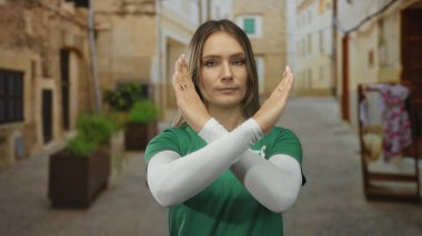 Yeşil tişörtlü bir kadın şehir caddesinde duruyor reddedilme jesti açık havada gündüz vakti şehir ortamında onaylanmadığını gösteriyor.