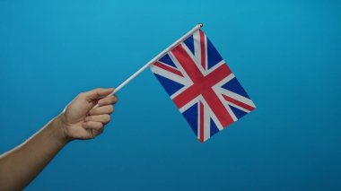Mavi arka planda İngiliz bayrağını tutan erkek el, vatanseverliği ve milliyeti sembolize ediyor canlı ve basit bir tasarımla sendika krikosunu gösteriyor..