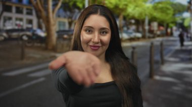 Genç İspanyol kadın, güneşli bir caddede gülümseyerek avucuna uzanıyor; dostça bir davetiye sıcaklığı.