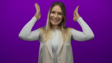 Canlı mor bir arkaplan karşısında gülümseyen bir kadın elleri yaratıcılık ve neşe gösteren bir çerçeve hareketi yapıyor..