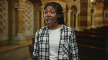 Örgülü saçları olan, göğsüne yumruk indirilmiş, ekose gömlek giyen, gözleri kapalı kilise sıralarında gülümseyen, manevi şükranlarını sunan bir kadın..