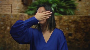 Şehir dışında, mavi gömlekli bir kadın, gün boyunca yeşil ve taş duvarlarla döşenmiş şehir caddesinde el pençe divan duruyormuş..