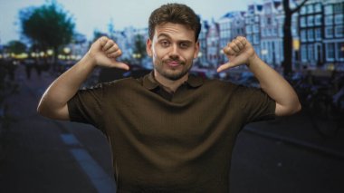 Şehir caddesinde göğsünü işaret eden, kanal evleri ve yakınlarda park etmiş bisikletleri olan bir adam..