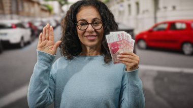 Bir şehir caddesinde elinde İzlanda Krona banknotları tutan kadın yemin jesti olarak elini kaldırıyor. Açık havada güven ve finansal bağlılığı simgeliyor..