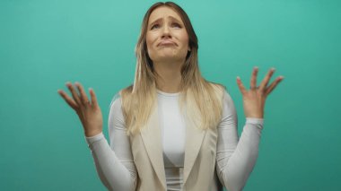 Sarı saçlı genç bir kadın, yeşil bir arka plan duvarına karşı hayal kırıklığını ifade ediyor, dışlanmış ve yukarı bakan bir portrede duygularını anlamlı hareketlerle ifade ediyor..