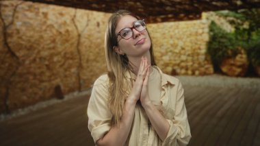 Sarışın kadın ahşap zemin ve taş duvarları olan taşra bir stüdyo binasında el ele tutuşuyor..