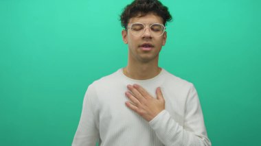 Yeşil stüdyoda kalp krizi için beyaz gömlek ve temiz gözlük takan genç adam gergin bir ifadeyle kalp krizi geçiriyor..