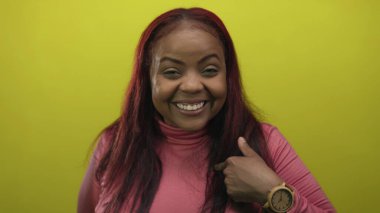 Yakın plan kadın geniş bir gülümseme ve kendini gösteren parlak sarı bir stüdyo; güven güçlendirici başarı.