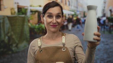 Genç İspanyol esnaf seramik kavanozu tutuyor ve sokak tabelasına imza atıyor. Onaylı gurur işçiliği kalitesi.