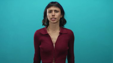 Bordo kazaklı genç İspanyol kadın stüdyoda avuçlarını açıp kamera görüntüsünü engelliyor..