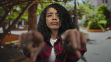 Kadın her iki işaret parmağı da yeşil ağaçların yanına ön cephe inşa ederek şehir caddesinde öne doğru işaret ediyor..