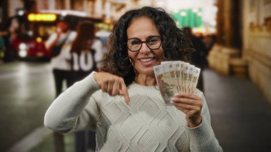 Şehir caddesinde elinde Rus rublesi ile gülümseyen ve gün içinde arka planda insanlar ve binalarla şehir dışını gösteren bir kadın..
