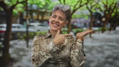 Beyaz kadın desenli tişört giyiyor gülümsüyor tamam işareti şehir caddesinde elini kaldırmış; onay.