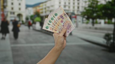 Arjantin pesolarını açık havada elinde tutan bir adam şehir ortamında para ve finans gösterisi yapıyor..