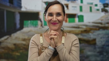 Deniz kenarında gülümseyen önlüklü bir kadın yeşil panjurlu, güneşli sahil manzarasında duygularını gösteren bir kadın.