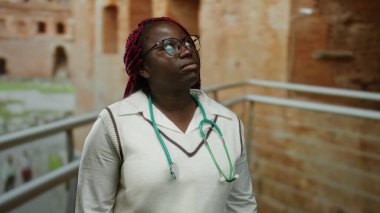 Gözlüklü bir kadın, steteskopla Roma harabelerini araştırıyor, şehir dışında tarih ve merak uyandırıyor..