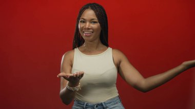 Genç Afro-Amerikalı kadın avuçlarını açıyor ve stüdyoda kameraya doğru gülümsüyor..