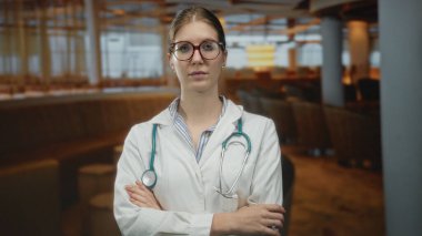 Gözlük takan genç sarışın kadın ve steteskoplu beyaz laboratuvar önlüğü otelde çapraz güven..