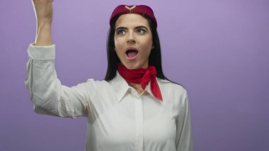 Üniformalı kadın mor bir duvar arkasına öpücük yolluyor, neşeli ve misafirperver bir jest sergiliyor..