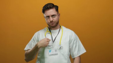 Turuncu bir duvarın üzerinden steteskop takan genç sakallı beyaz doktor kendine güvenerek profesyonel kimlik ve tıbbi uzmanlık gösteriyor..