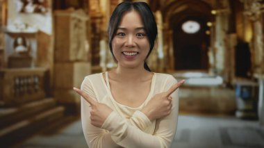 Kilisenin iç kısımlarında gülümseyen bir kadın, iki eliyle şakacı bir şekilde, esinlenerek ve hoş karşılayan bir atmosfer sunuyor..