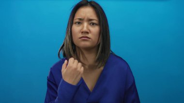 Stüdyo ortamında gücünü ve duygularını ön plana çıkaran sert mavi arka planda kararlı bir kadın görülüyor..