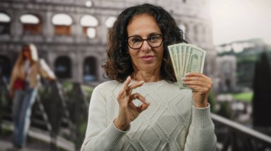Roma Kolezyumu 'nun yanında Amerikan doları tutan kadın, sembolik bir İtalyan açık hava şehrinde seyahat ve finans unsurlarını birleştirerek iyi bir jest yapıyor..