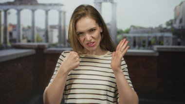 Genç kadın, Antik Roma binasında doğrudan kamerayı işaret ediyor; öfke gerilimi karşı koyma hüsranı.