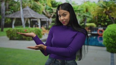 Kadın, açık hava otel ortamında avuçlarıyla ve gülümseyen yüzüyle tatil köyü havuzunda baş parmağını kaldırıyor; iyimserlik.