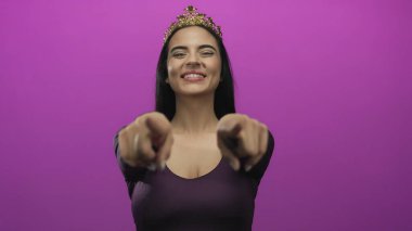 Taçlı bir kadın parlak bir şekilde gülümserken aynı zamanda canlı pembe bir arka plana bakarak pozitifliği ve güveni işaret ediyor..