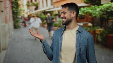 Genç adam, bulanık yayalar ve Avrupa mimarisinin yer aldığı büyüleyici bir şehir caddesinde gülümsüyor..