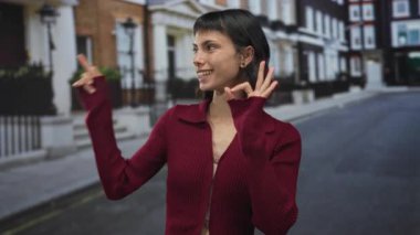 Latin kökenli genç bir kadın şehir sahnesinde iyi niyet göstergesi gösterirken, neşeyi onaylıyor..