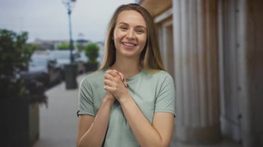 Şehir sokaklarında sevinçle gülümseyen bir kadın umut dolu bir jest içinde şehir manzarası ve yeşillik ile çevrili açık havada..