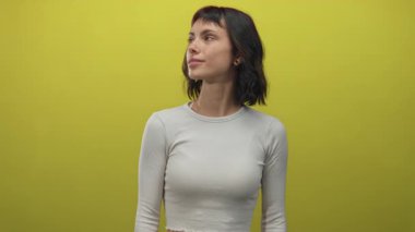 Kadın parlak bir gülümseme ve yüzünü çerçeveleyen koyu renk saçlarla başını eğiyor stüdyoda çillerini gösteriyor; iyimserlik.