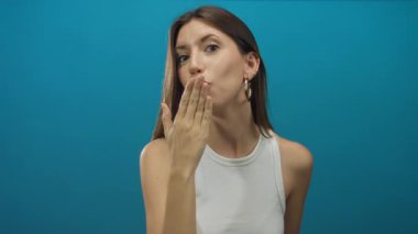 Stüdyoda uzanmış bir elle öpüşen bir kadın, halka küpeler görünür, dudaklar büzüşmüş, şefkat.