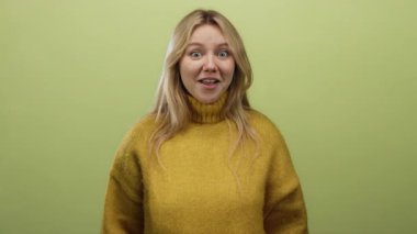Yeşil arka planda sarı süveter giyen bir kadın.