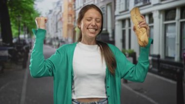 Şehir caddesinde elinde baget tutan ve yumruk sallayan kadın yeşil hırka ve beyaz hasat bluzu ile; sevinç kutlamaları.